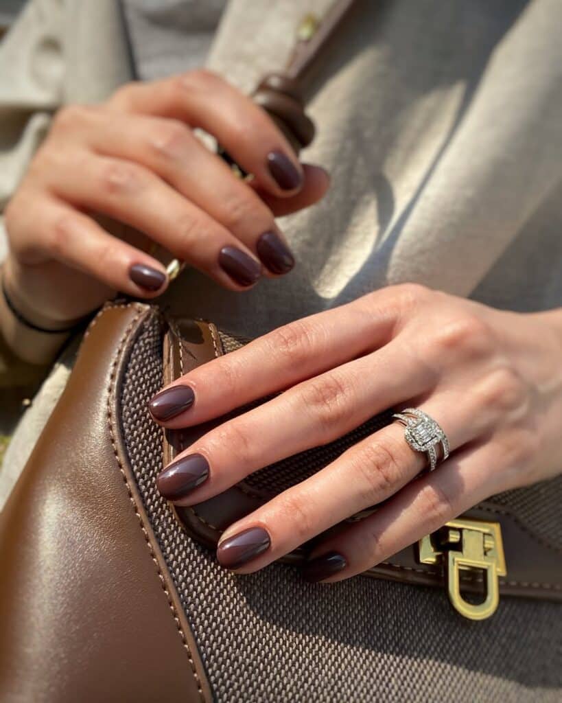 Glossy mocha-colored nails on a medium skin tone.