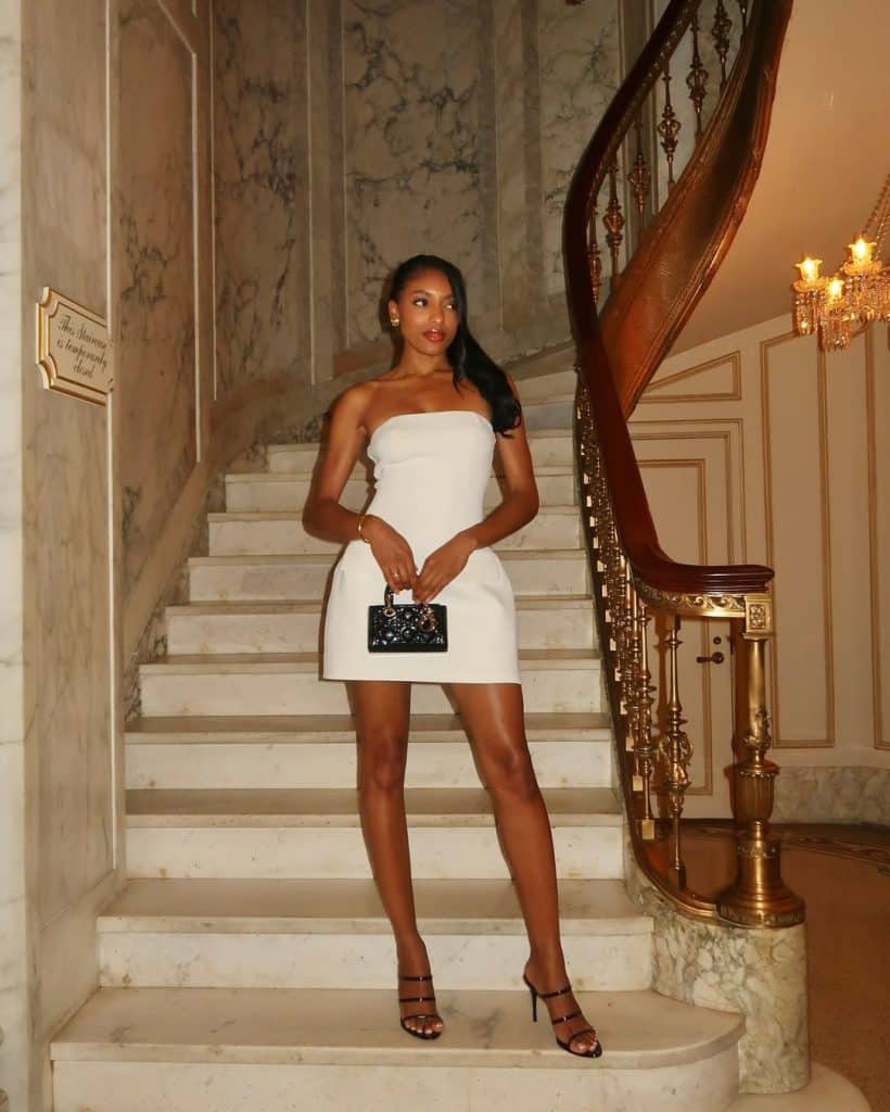 Woman in a white strapless mini dress on a marble staircase.