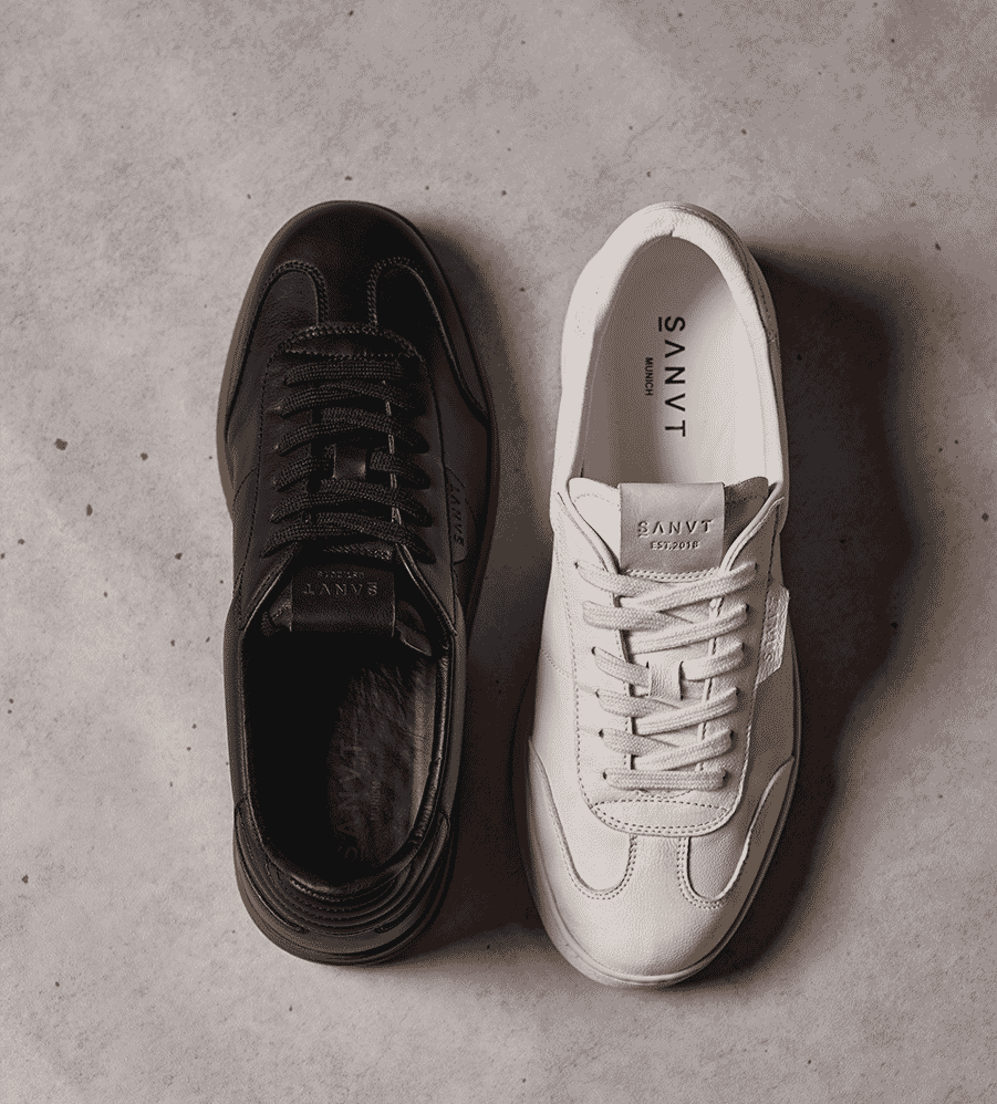 A pair of sustainable white minimalist sneakers by SANVT against a neutral background.