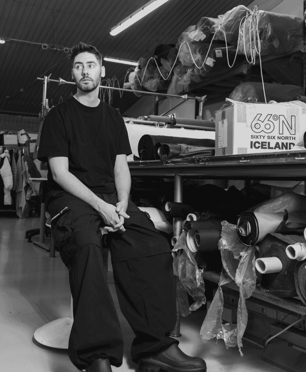 A person in a utilitarian workshop surrounded by fabric rolls and 66°North branding.