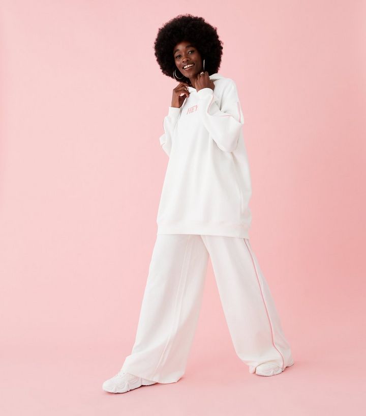 A woman in a white oversized hoodie and wide-leg sweatpants showing a long-line silhouette.