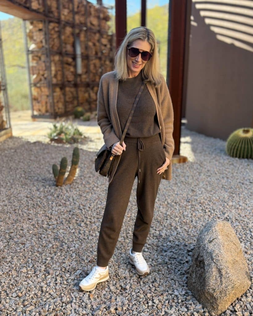 A woman in a coordinated brown knit cardigan and joggers standing in an outdoor setting.