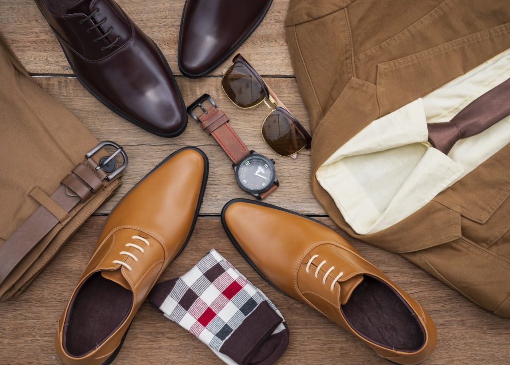 A flat-lay of brown leather dress shoes, khaki trousers, and business accessories.