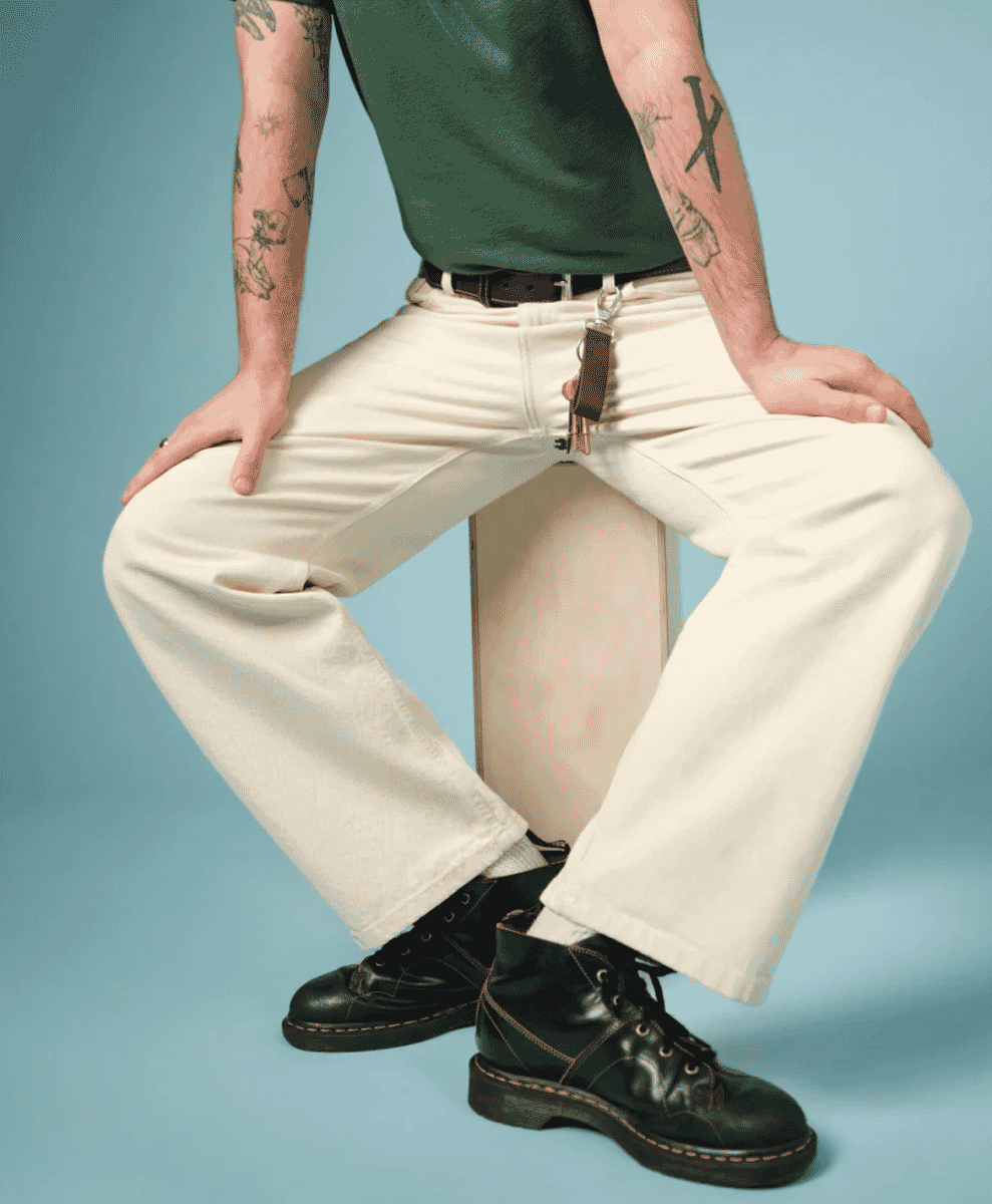Man wearing straight jeans and a layered patterned overshirt over a t-shirt.
