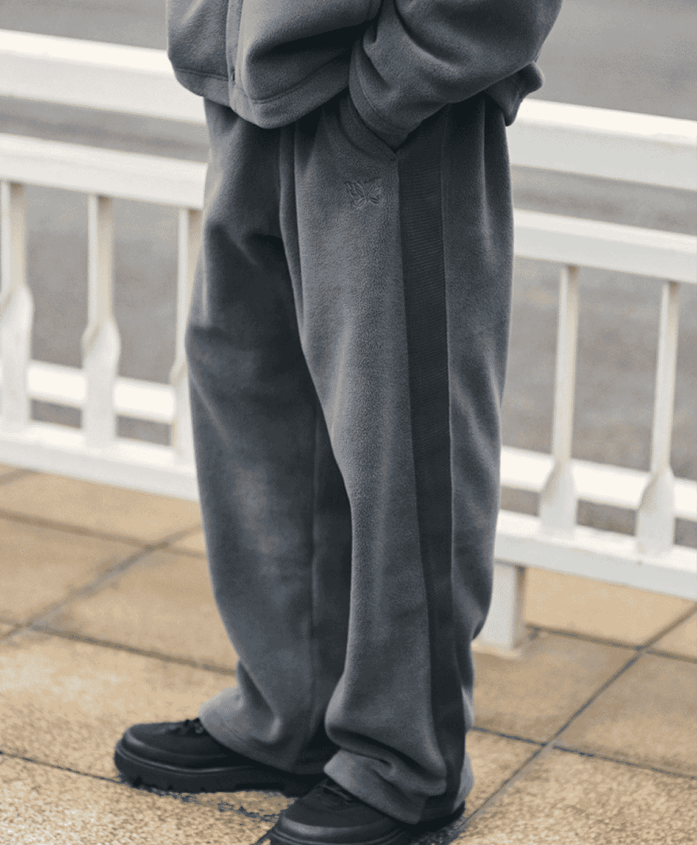 Close-up of dark gray fleece sweatpants featuring the embroidered butterfly motif.