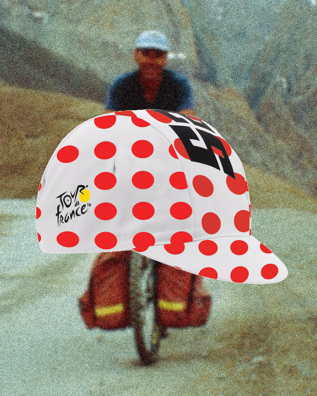 A cycling cap resting beside a latte and a carbon helmet on a wooden cafe table.