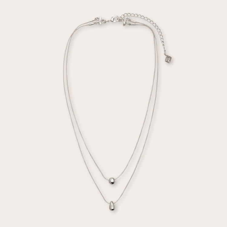 A layered metal pendant necklace featuring both silver and gold tones.