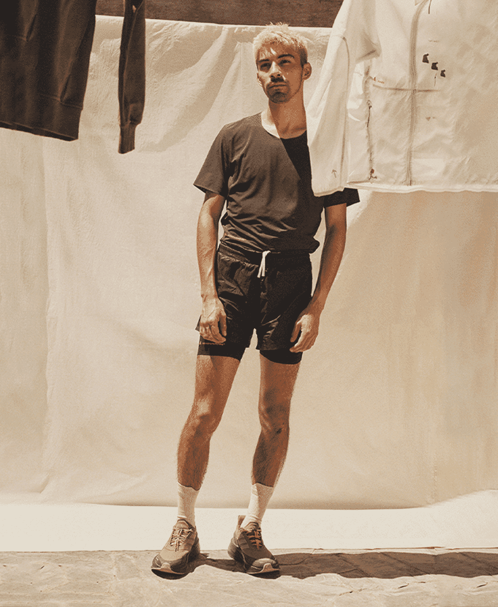 A man wearing layered black t-shirts and shorts with technical running shoes.