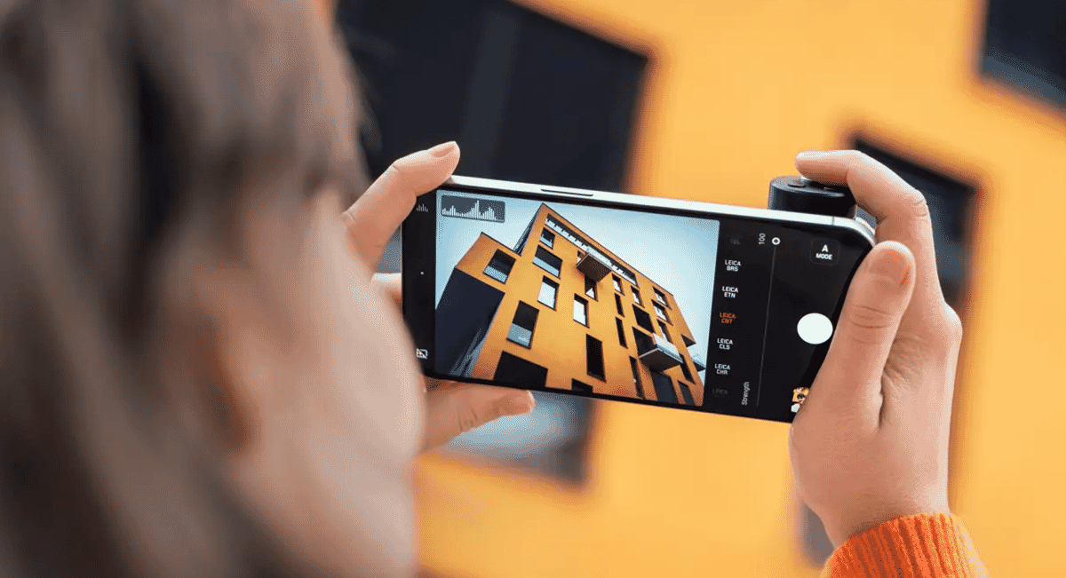 A person photographing a modern yellow building using an iPhone.