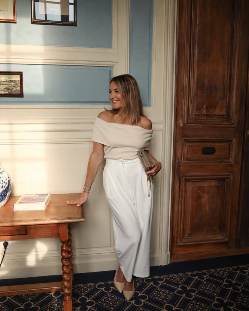 Woman in a cream top and white wide-leg trousers.