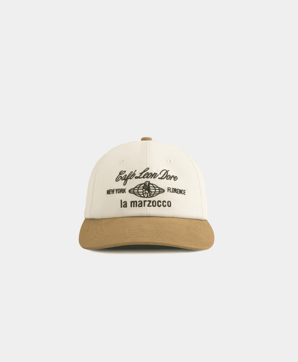A two-tone cream and tan baseball cap with Café Leon Dore and La Marzocco embroidery.