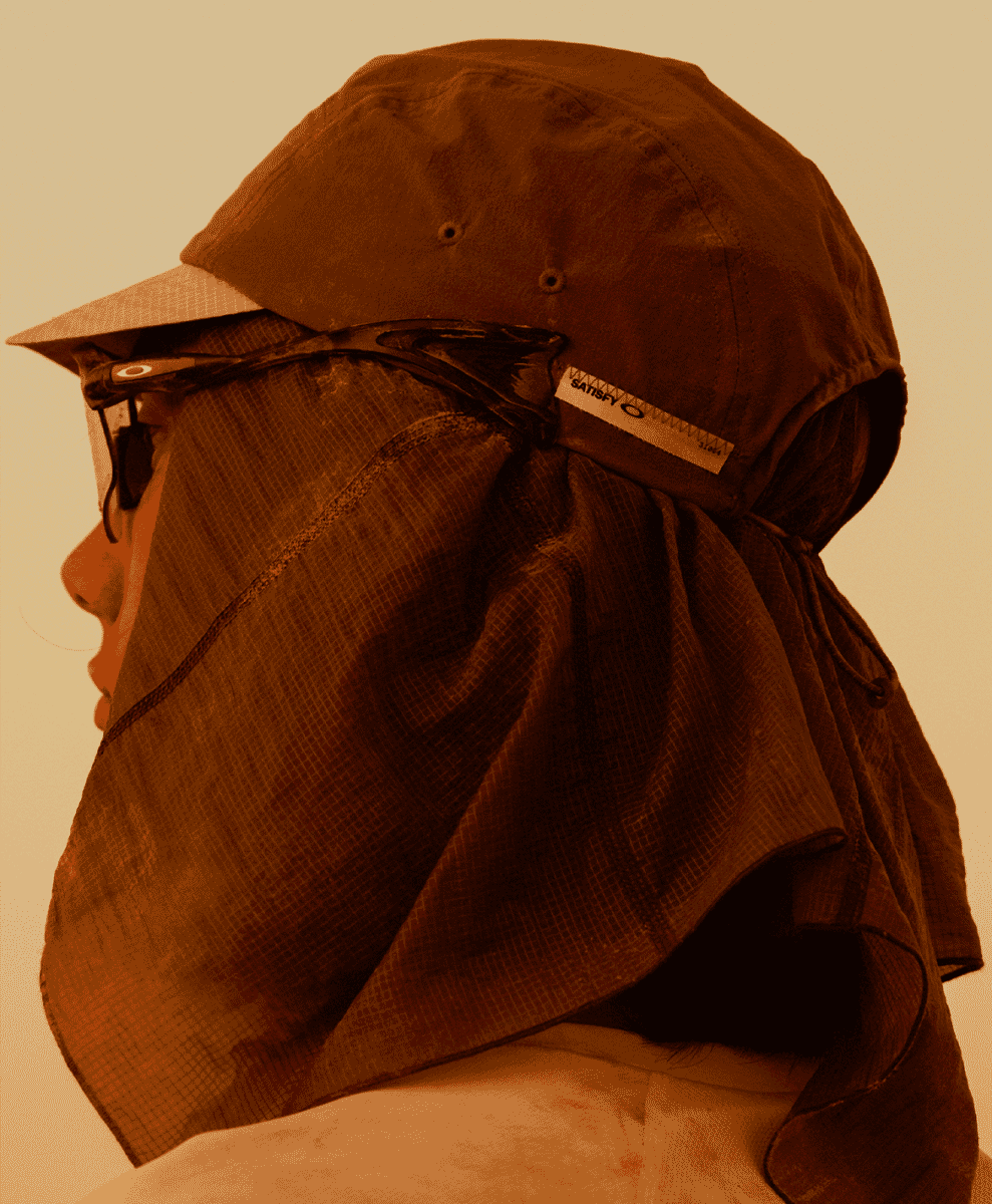 Detail shot of a brown running cap with a long protective neck flap and technical sunglasses.