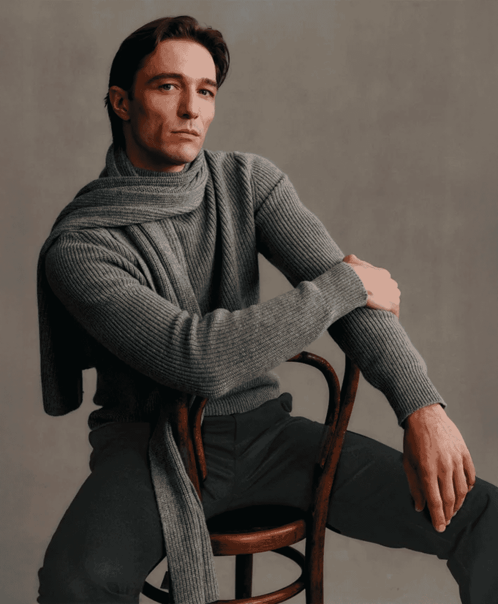 Man wearing a grey ribbed turtleneck sweater with a matching scarf.