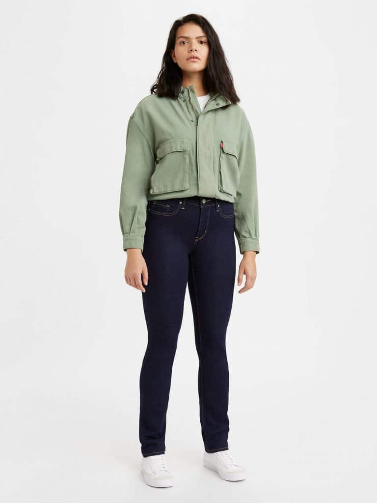 A woman in a cropped olive green utility jacket and dark blue tall-fit jeans.