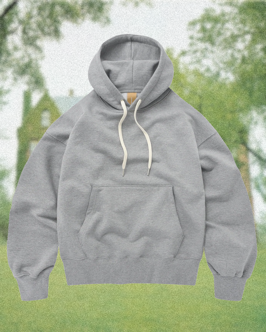 A neatly folded stack of grey marl hoodies on a minimalist wooden wardrobe shelf.