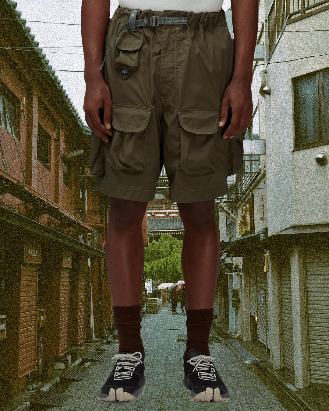 Model wearing olive cargo shorts and dark Tabi-style shoes in a Japanese alley.