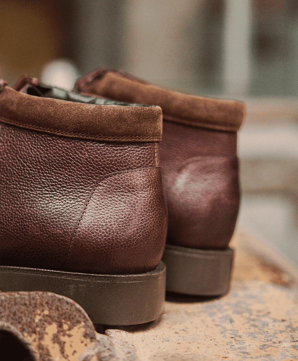 Close-up of brown leather and suede moc-toe boots with textured soles.