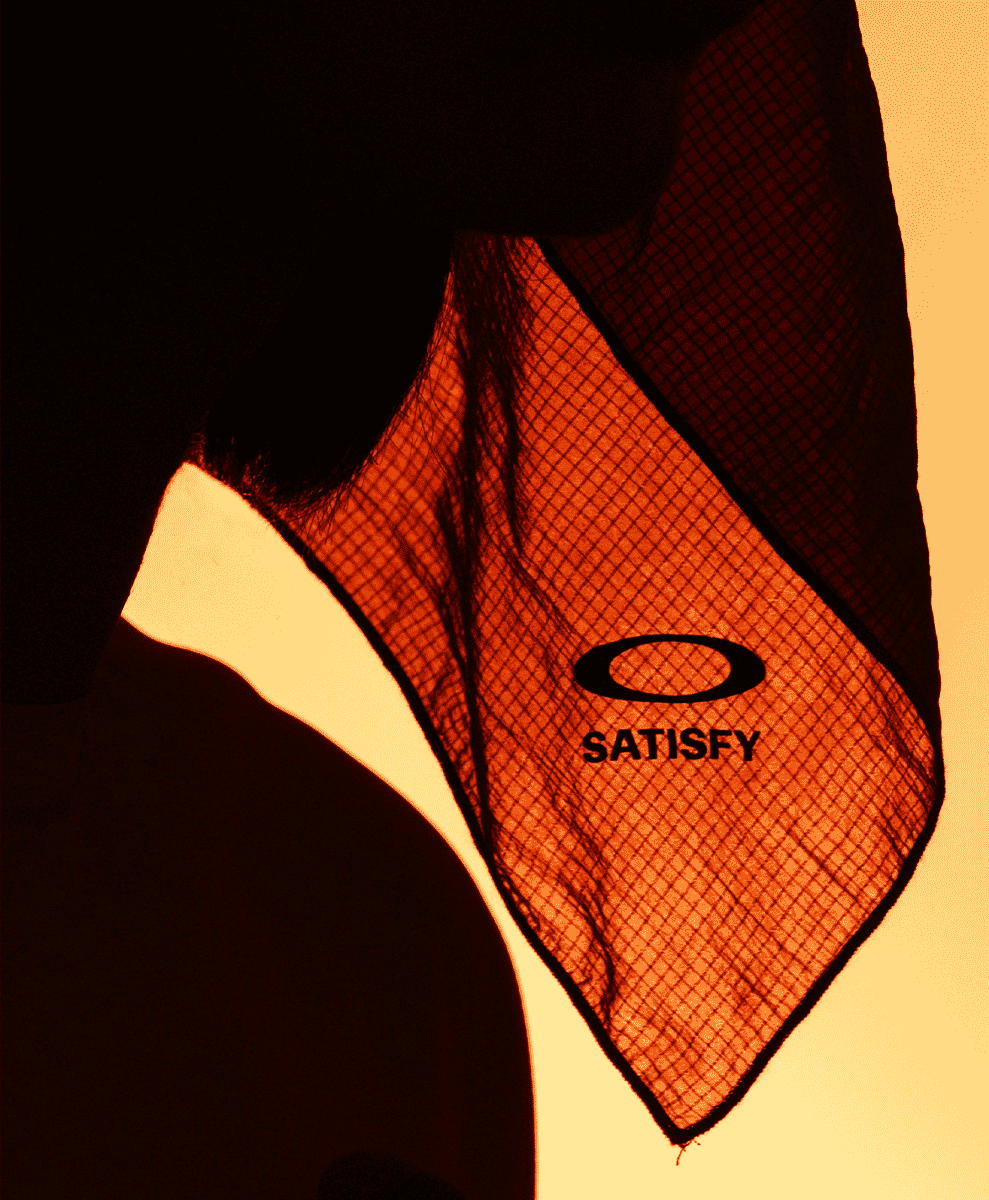 Close-up of a mesh neck gaiter showing the Oakley and Satisfy logos through a breathable weave.