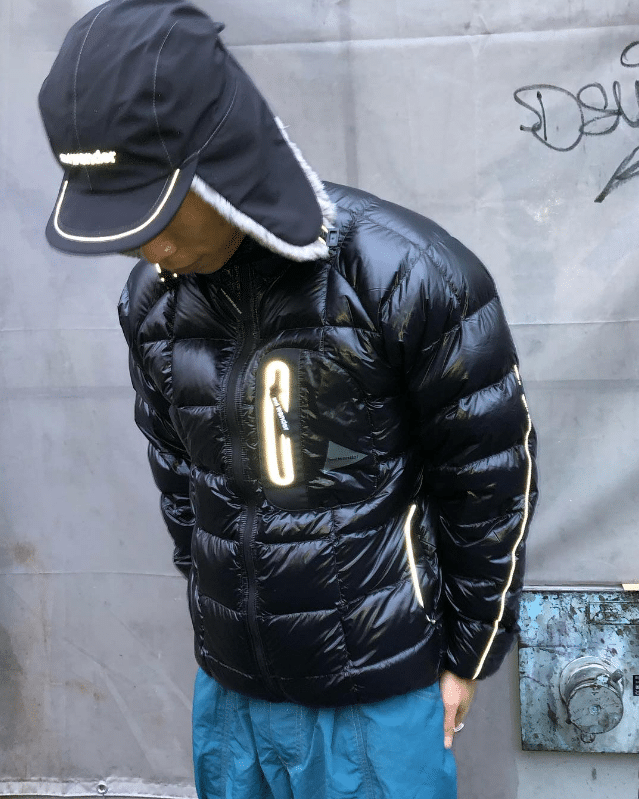 Person in a black puffer jacket with reflective stripes and matching headwear.