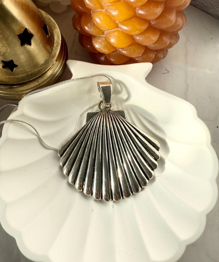 A large shell pendant necklace on a gold chain.