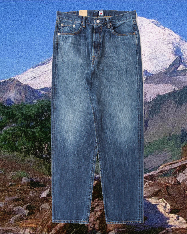 Medium-wash blue denim jeans with a straight-leg cut in a rugged landscape.