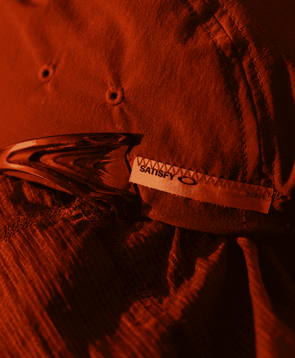 Macro view of a Satisfy and Oakley branded tag stitched onto a technical textured fabric.