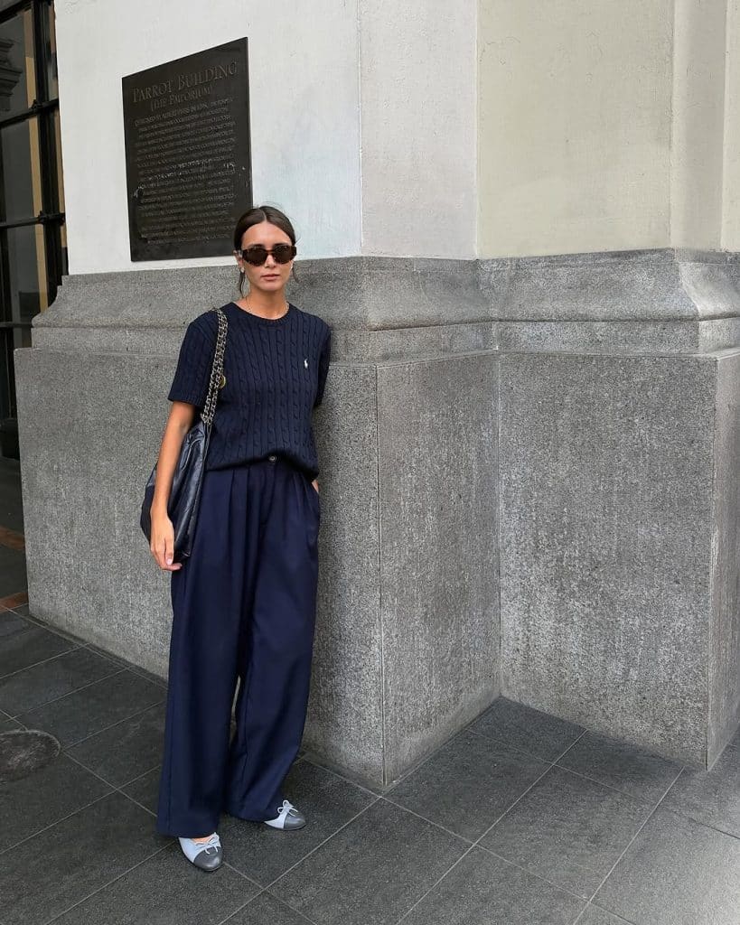 A woman in a navy cable-knit sweater and matching wide-leg trousers.