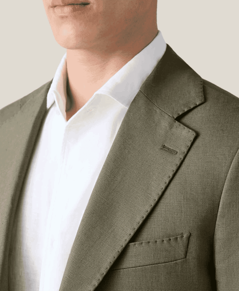 Close-up of an olive-green suit jacket showing the shoulder seam and lapel detail.
