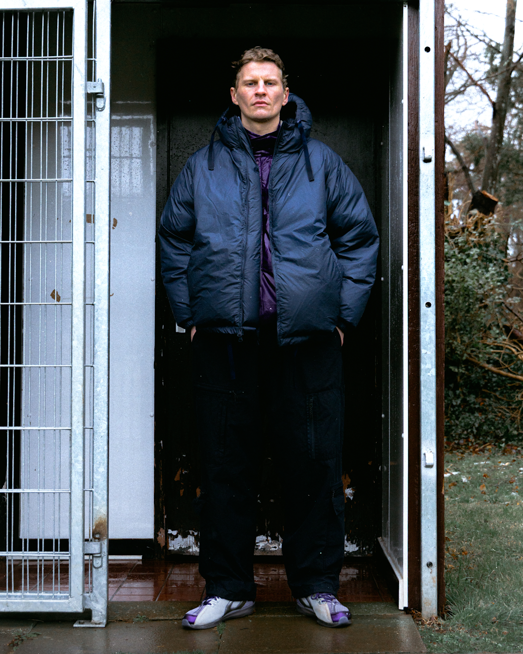 Hero shot of a JUGEM technical parka in a rainy city street.