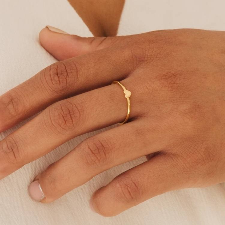 Minimalist gold heart-shaped ring on a white background.
