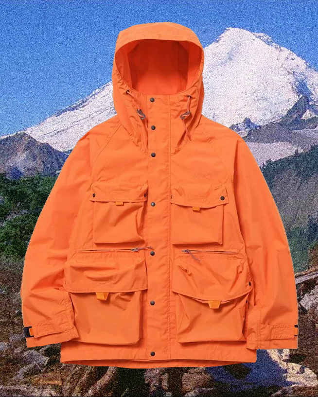 Bright orange hooded mountain parka with multi-pocket design against a snowy peak.