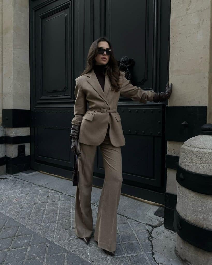 Woman wearing a belted camel-colored blazer and matching wide-leg trousers.