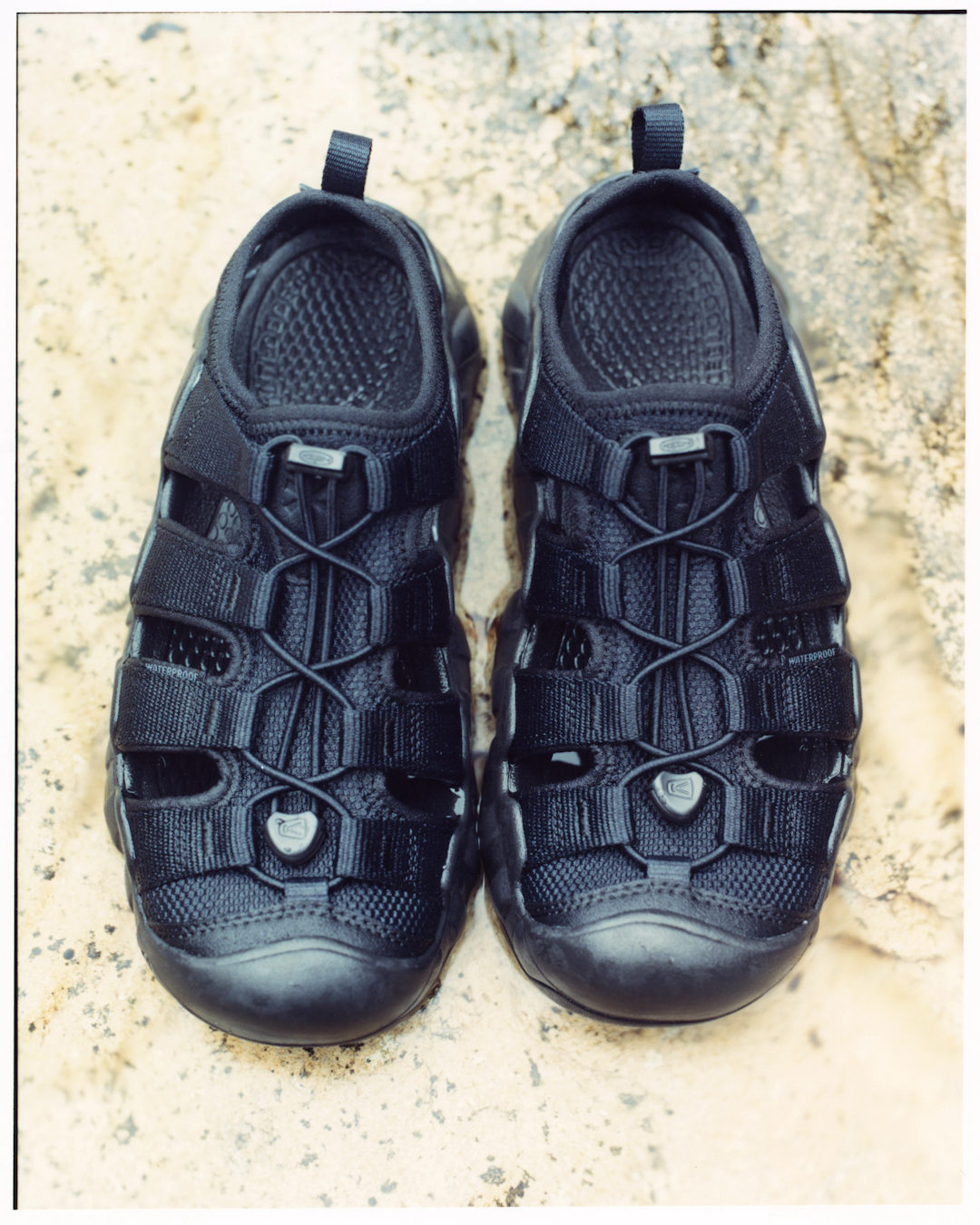 Lifestyle shot of the Snow Peak KEEN sandals in a modern urban architectural setting.