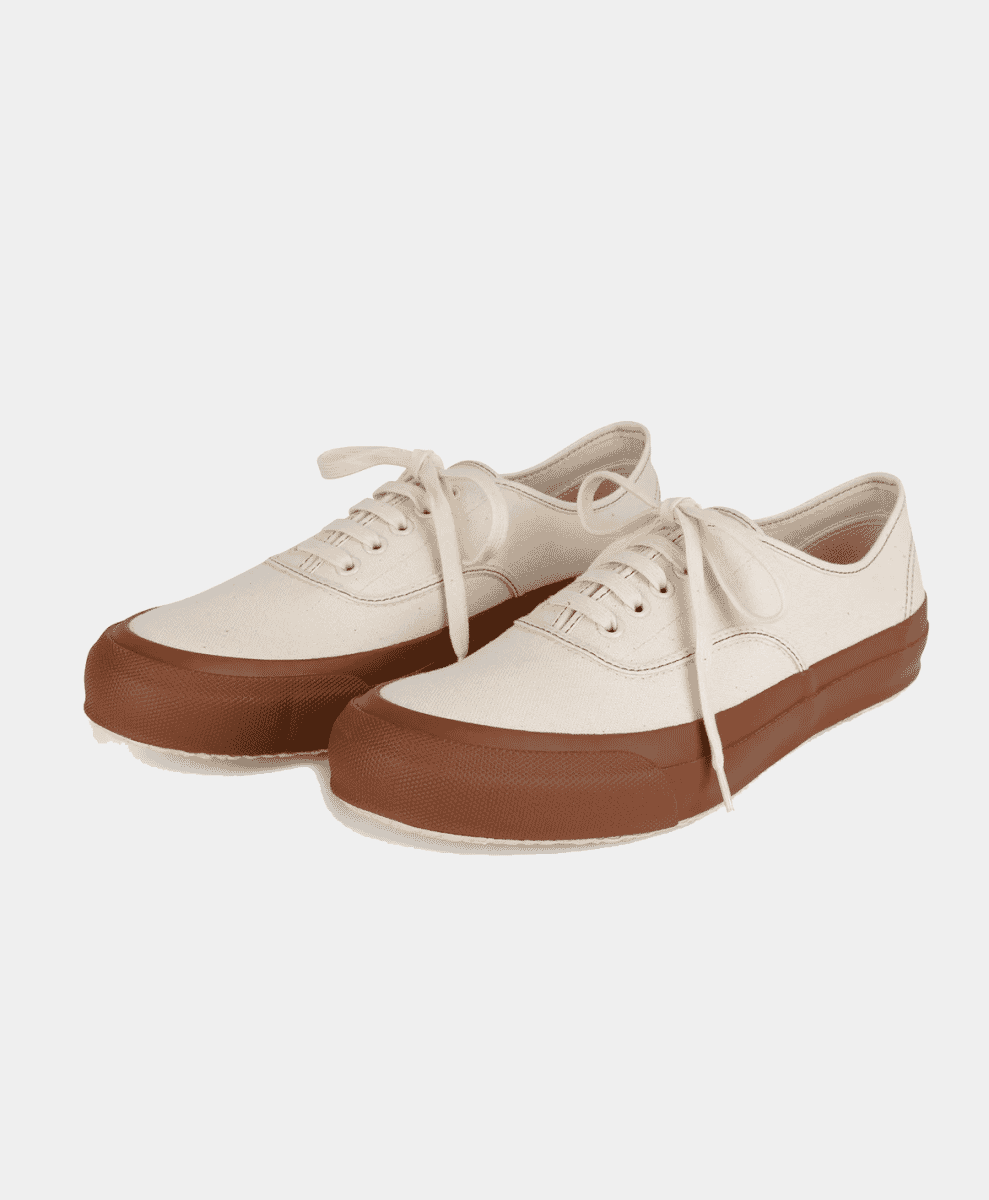 Cream-colored canvas sneakers with brown rubber soles and matching laces.