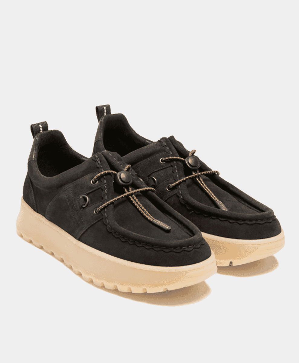 Black suede slip-on sneakers with chunky beige soles and toggle laces.