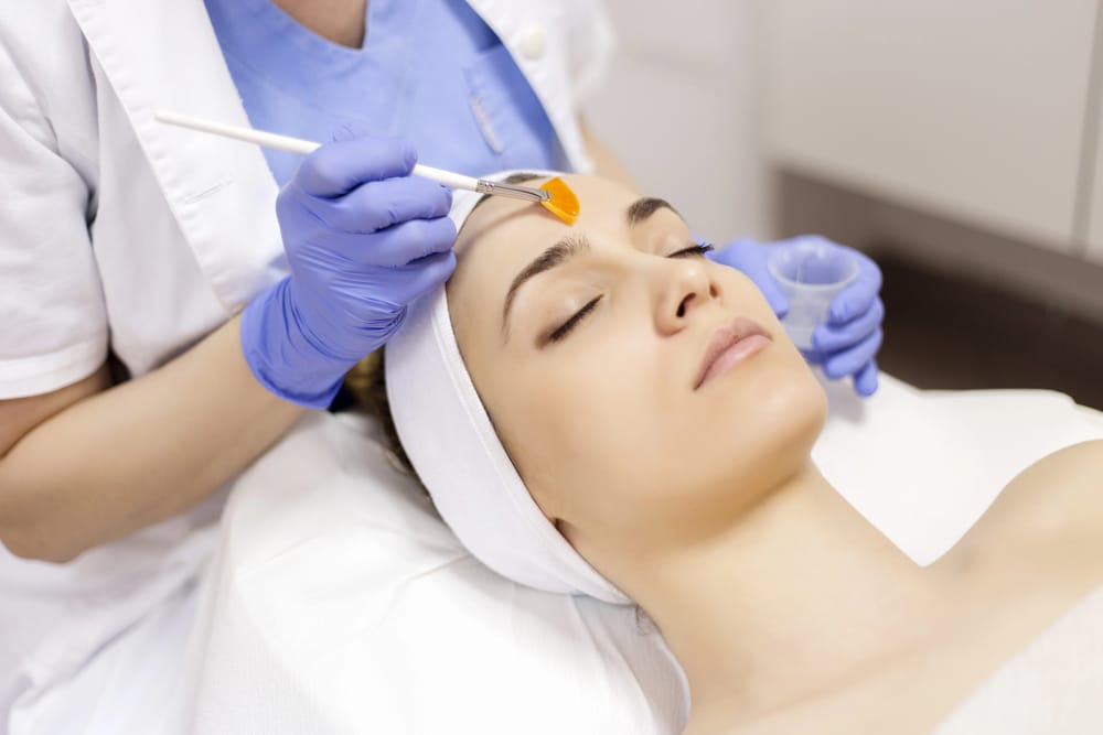 A close-up of a facial treatment in a clinic with the practitioner wearing blue gloves.