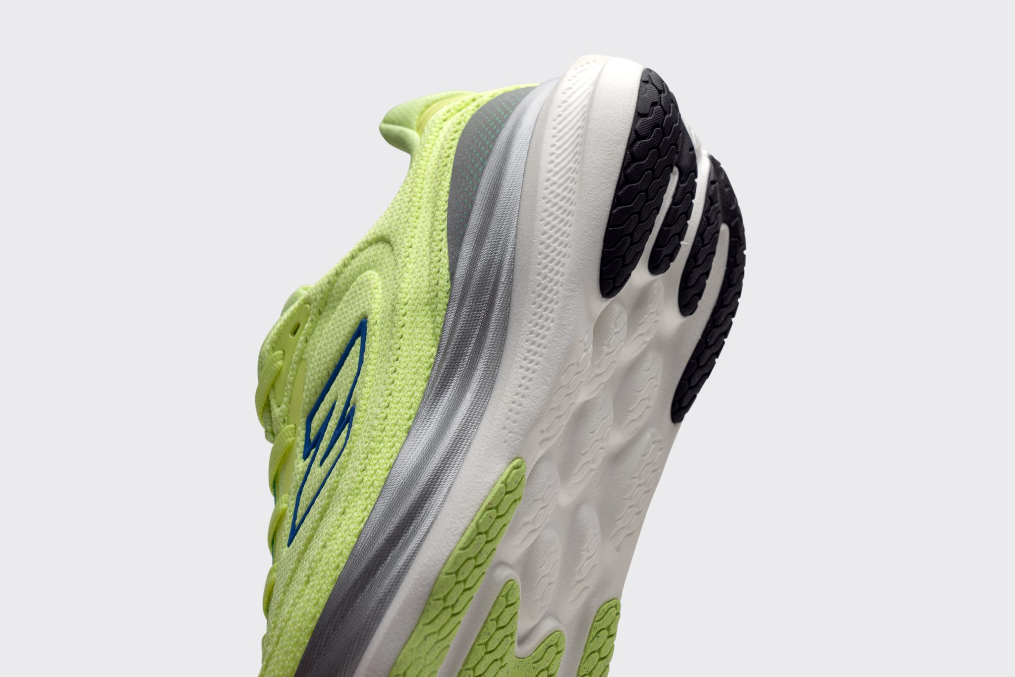 Close-up of a neon green running shoe with a thick white midsole and black traction pods.