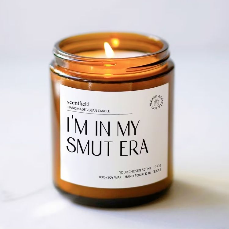 A scented candle labeled Smut Era in a glass jar.