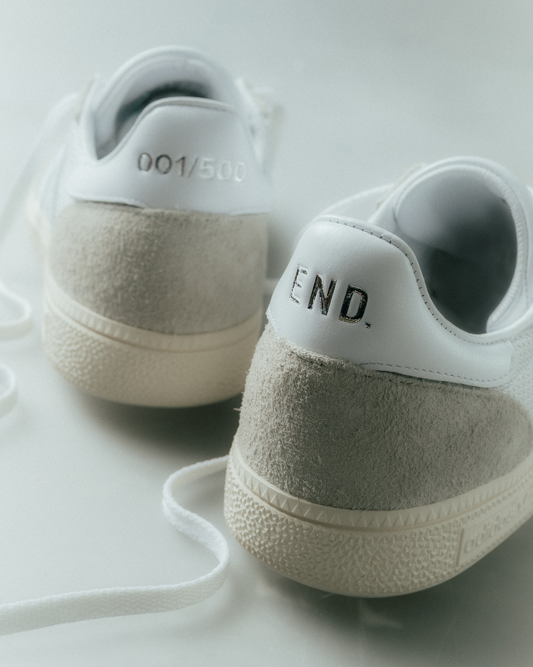 On-feet shot of the white and grey adidas sneakers styled with wide-leg denim trousers.