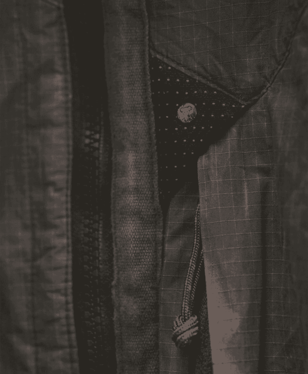 Macro shot of grid-patterned technical fabric on a jacket with a branded button and dotted lining.