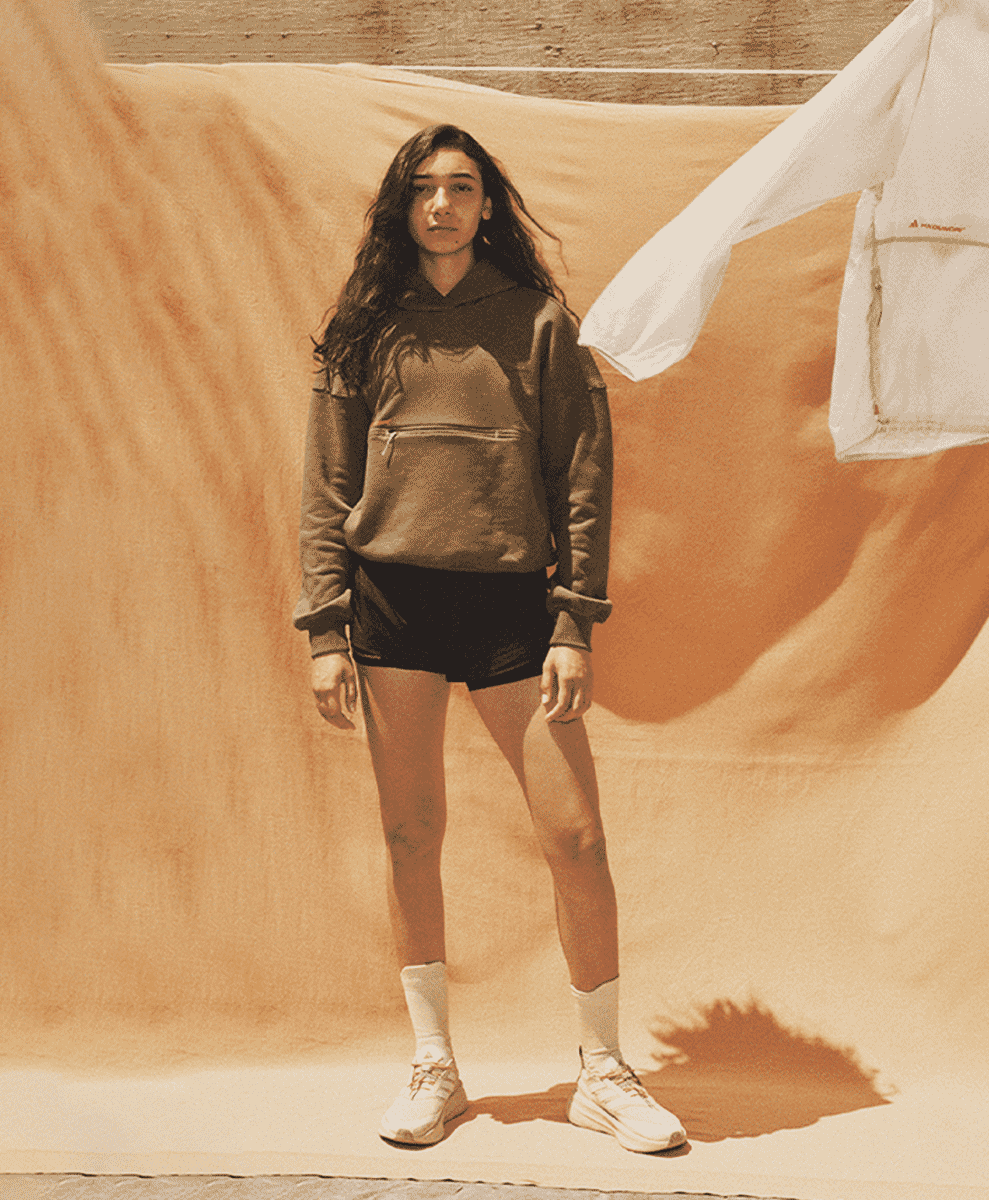 A woman wearing a relaxed-fit brown hoodie and black shorts.