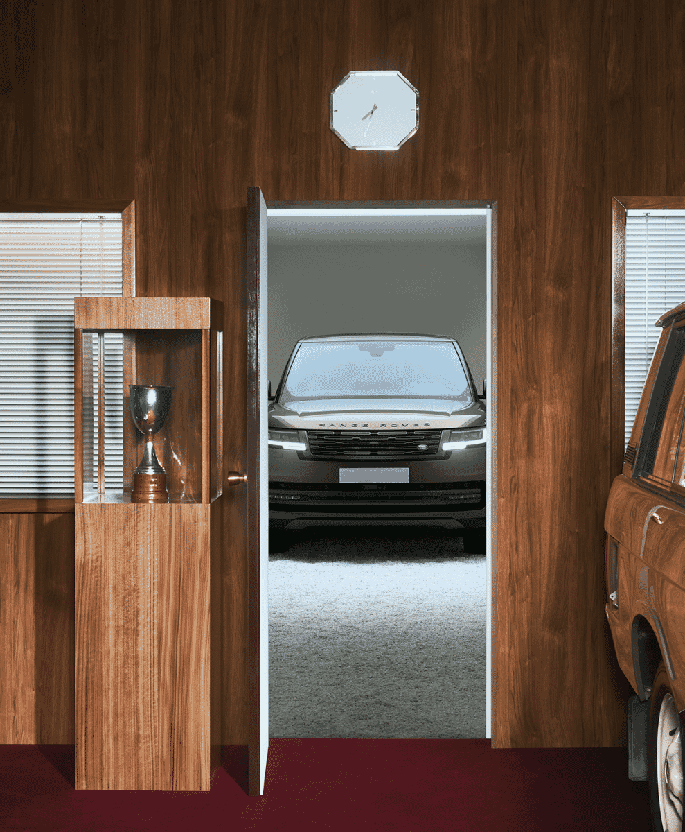 A modern Range Rover framed by an open vintage doorway with wood paneling.