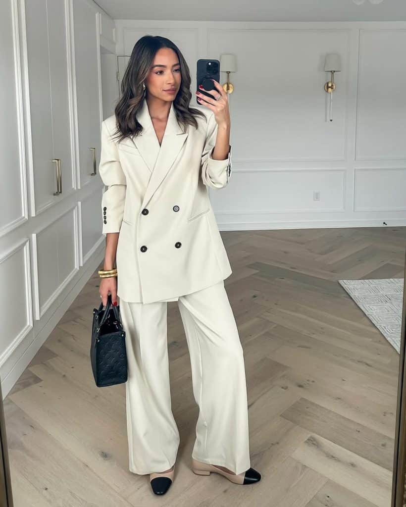 A mirror selfie of a woman in a cream double-breasted blazer suit.