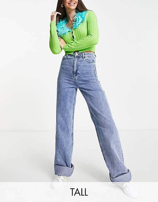 A woman in a vibrant lime green cardigan and high-waisted wide-leg jeans.
