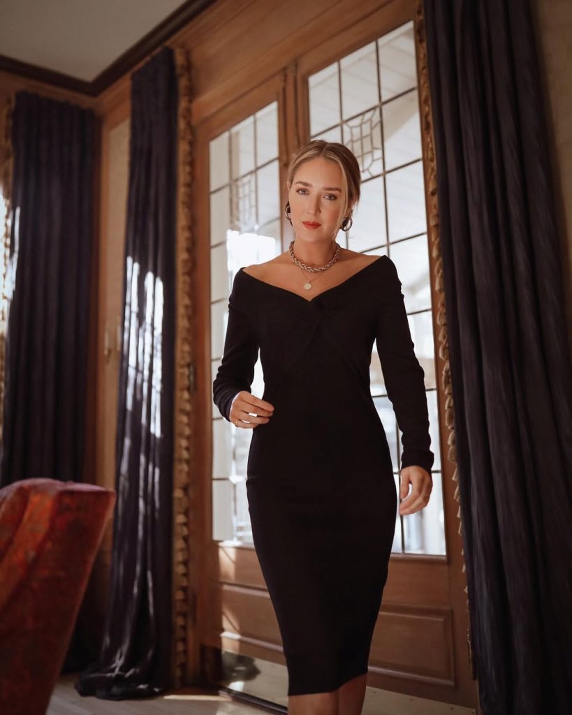 A woman in a black off-the-shoulder dress with an elegant necklace.