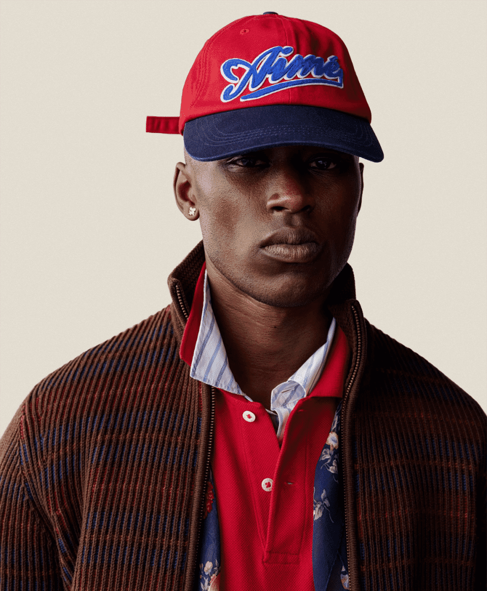 Model in a blazer, knit shirt, and technical accessories.