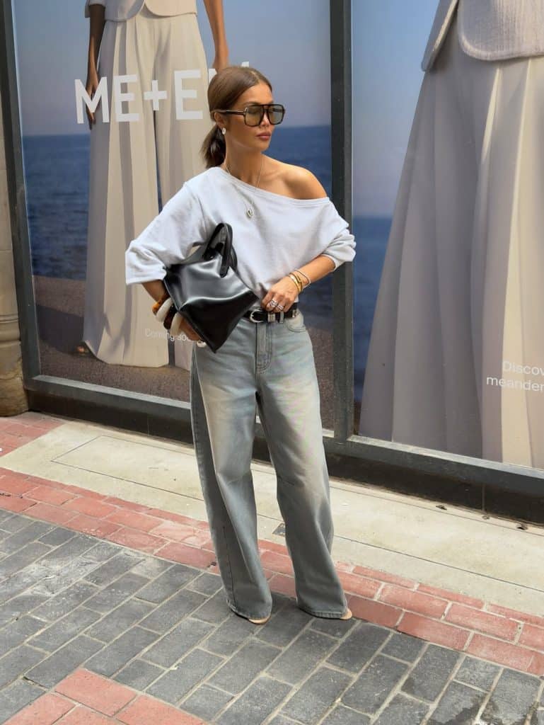 A woman in an off-shoulder white top and wide-leg light-wash jeans.