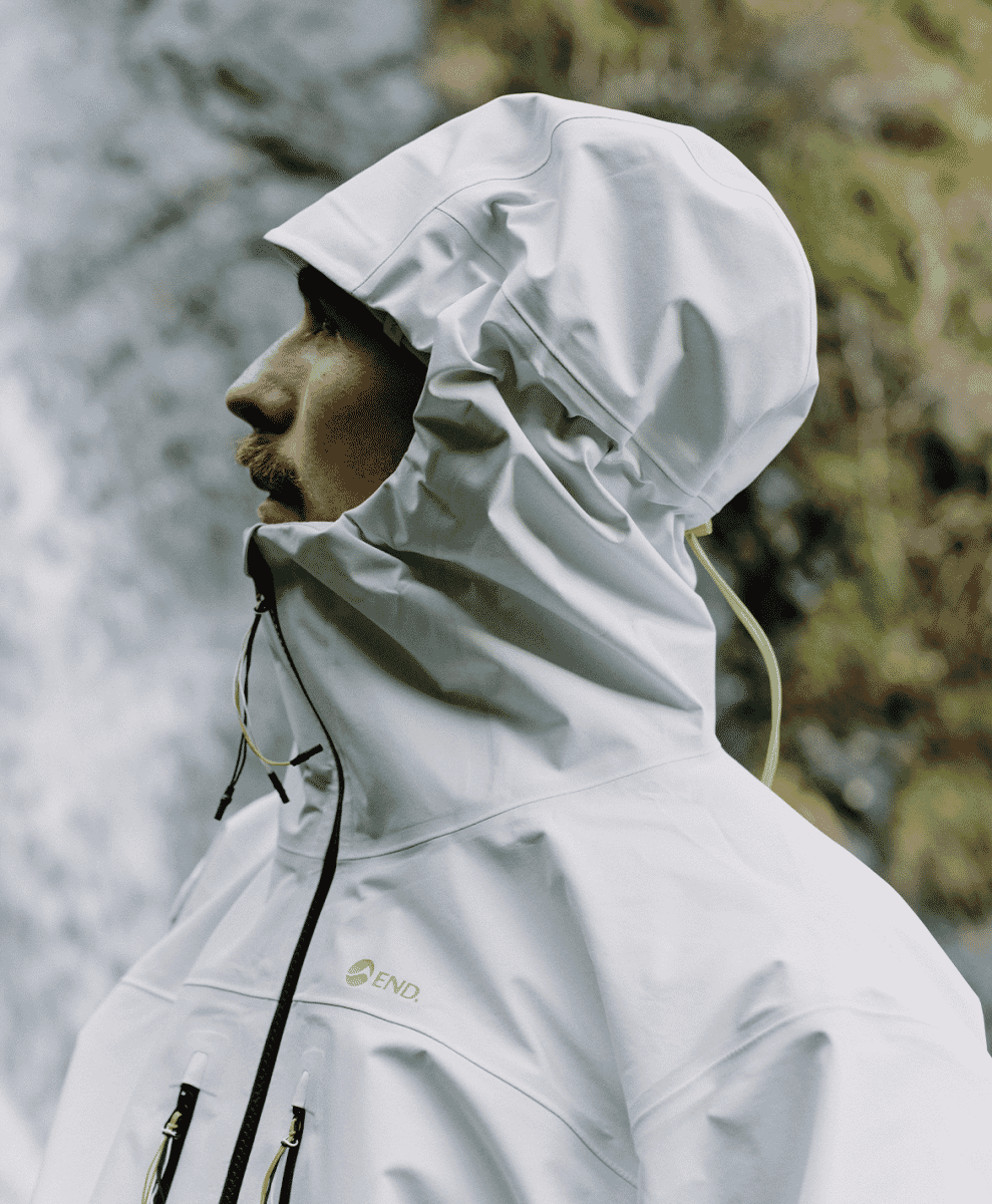 Profile shot of a man in a white hooded jacket featuring END. branding on the side of the hood.