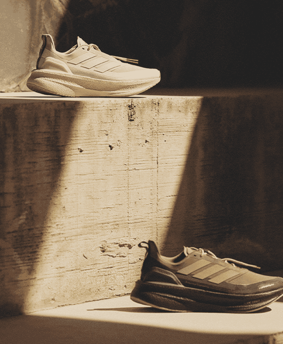 Two pairs of Adidas sneakers in white and dark gray shown side-by-side in a sepia-toned setting.