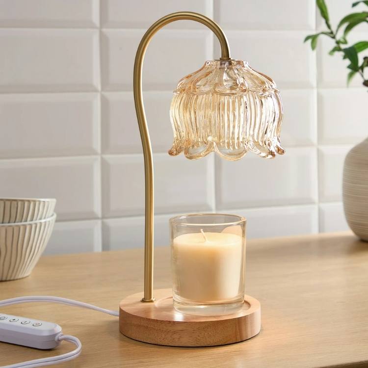A black candle warmer lamp positioned over a glass jar candle.